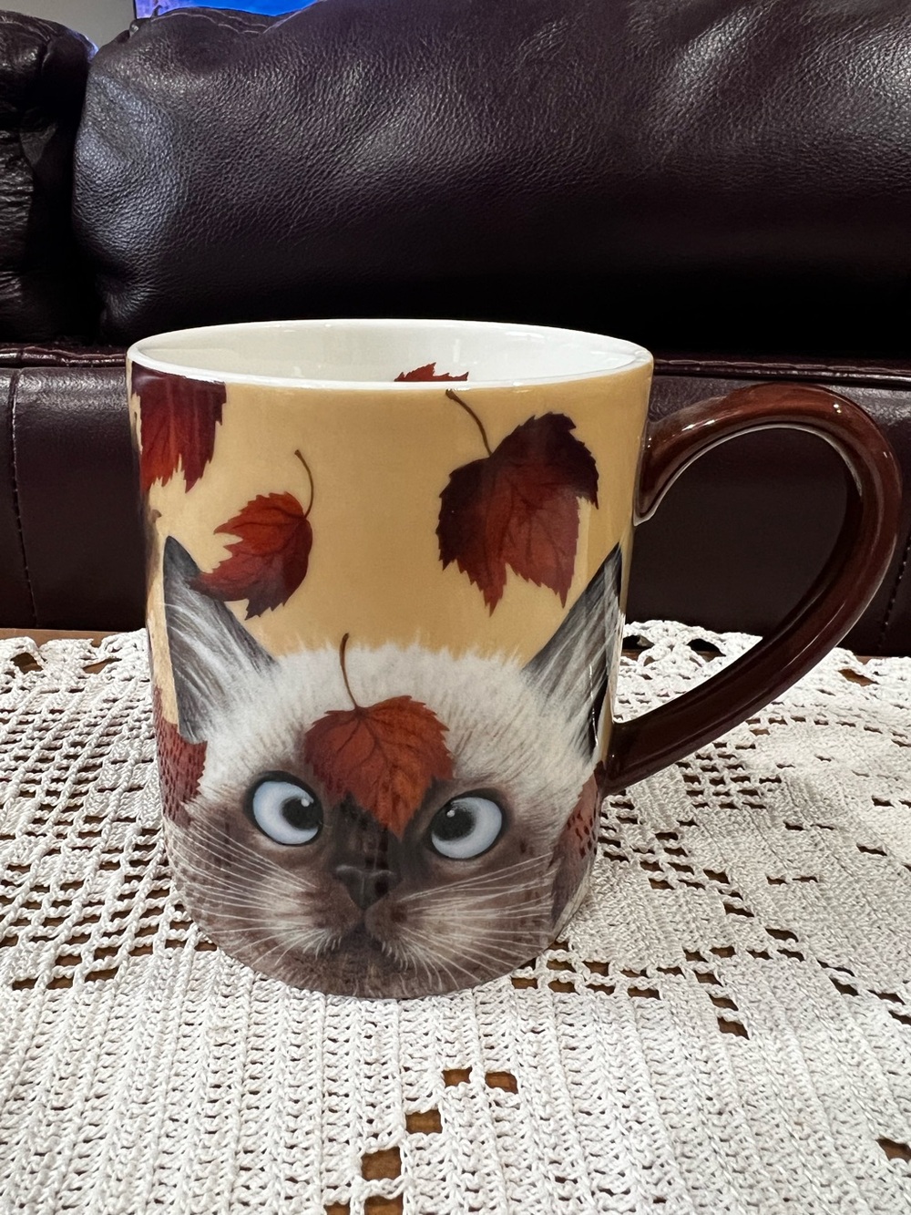 This is a LANG Catching Leaves ceramic coffee mug featuring artwork of a cat.
